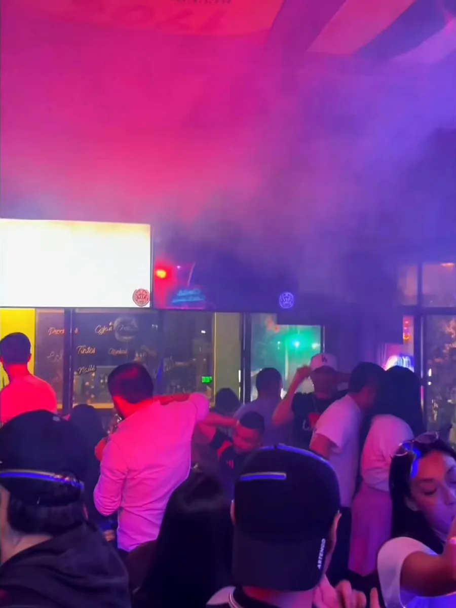 Salón de VIP Capital lleno una noche de karaoke, con luces magenta y pantalla encendida